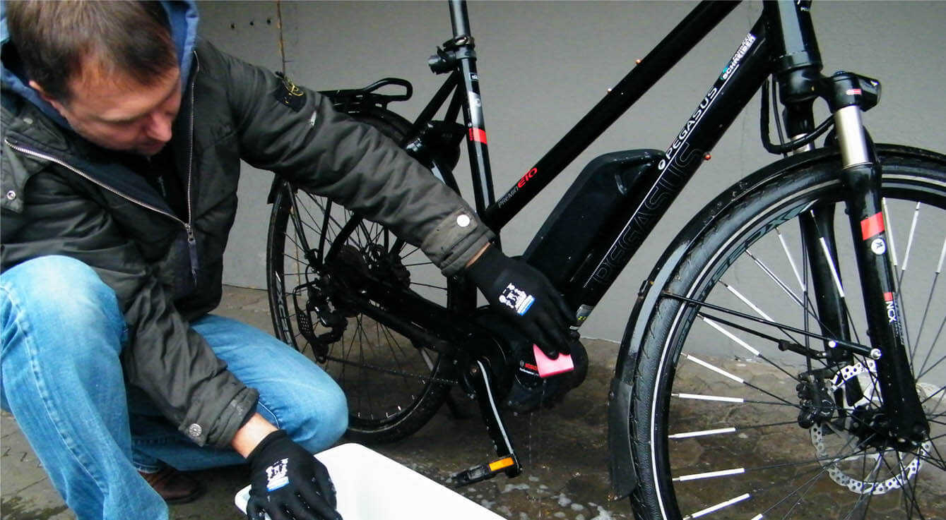 Mann putzt mit einem schwamm ein E-Bike