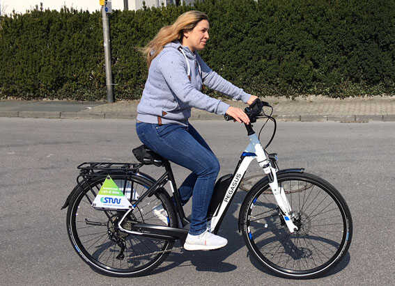 E Bike / Pedelec Testen Frau fährt mit einem Pegasus E Bike die Strasse entlang